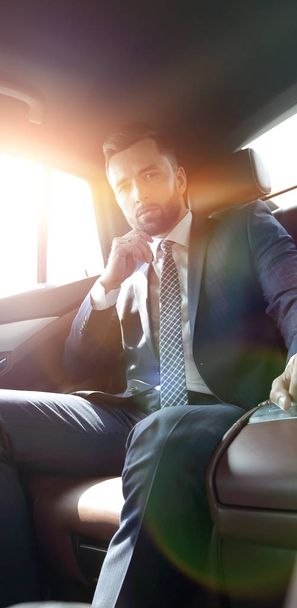 Successful man sitting in the back seat of a car - Foto, Bild