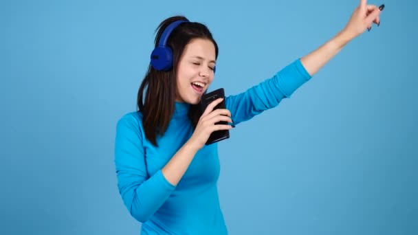 Happy woman wearing headphones and singing in her smartphone - Footage, Video