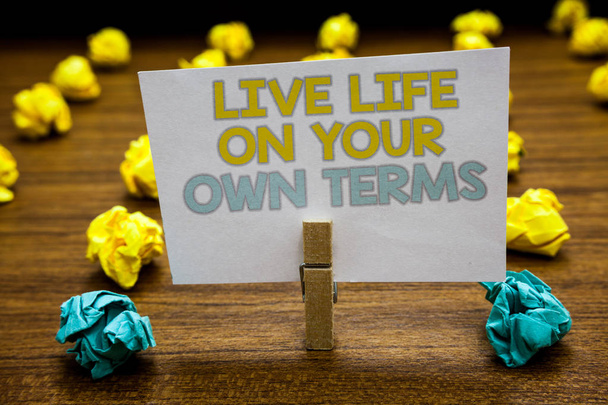Writing note showing Live Life On Your Own Terms. Business photo showcasing Give yourself guidelines for a good living Written notepad stand with paperclip yellow blue lobs on wooden deck - Photo, Image