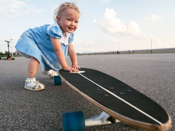Street Sport: Happy girl in riding a longboard on the pavement and puddles. - Fotoğraf, Görsel