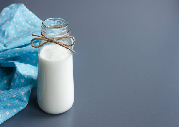 small glass bottle of drinking yogurt, homemade and traditional, gray table background with blue linen napkin, copy space - Fotó, kép