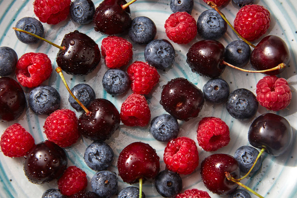 Close-up of summer organic berries on blue ceramic plate. Concept of healthy eating. Top view. - Φωτογραφία, εικόνα