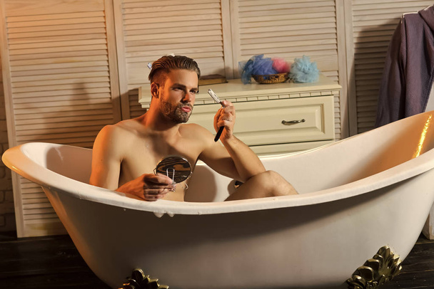 Bearded young man holding retro shaving tools - Foto, afbeelding