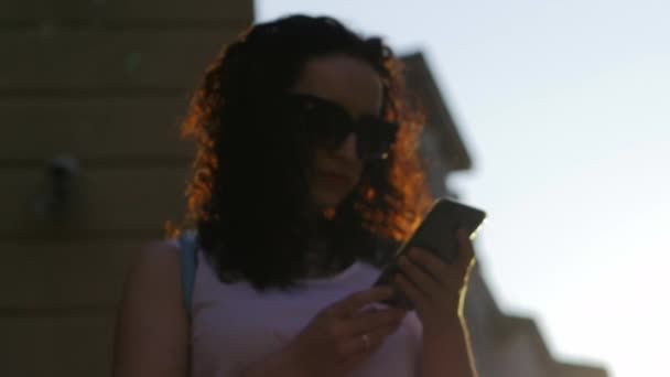 Gyönyörű nő beszél a telefonon a szabadban. Egy nő-val szemüveg. Lassú mozgás. 4k - Felvétel, videó