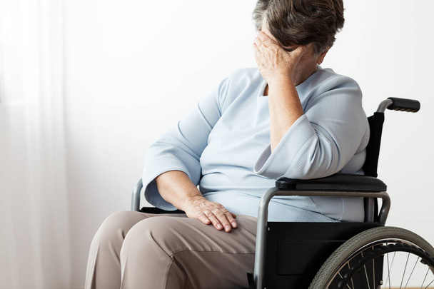 Sad disabled senior woman in a wheelchair in a nursing house - Фото, зображення
