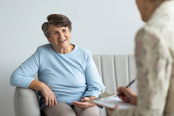 Smiling senior woman talking to a psychologist about happy life of a pensioner - Fotó, kép