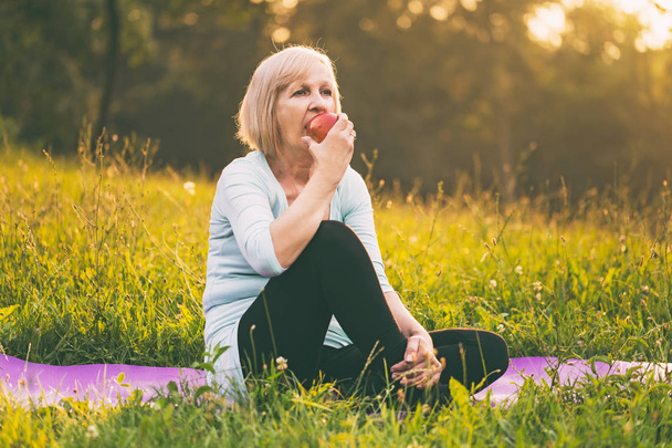 Femme âgée active mangeant de la pomme après l'exercice.L'image est intentionnellement tonique
. - Photo, image