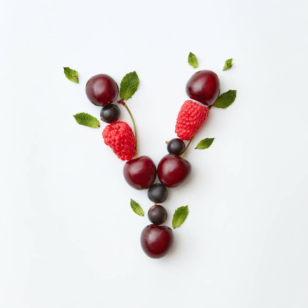 Letter Y of English alphabet made of natural organic berries, ripe fresh raspberries, black currant, cherries, green mint leaves on white background - Foto, Imagem