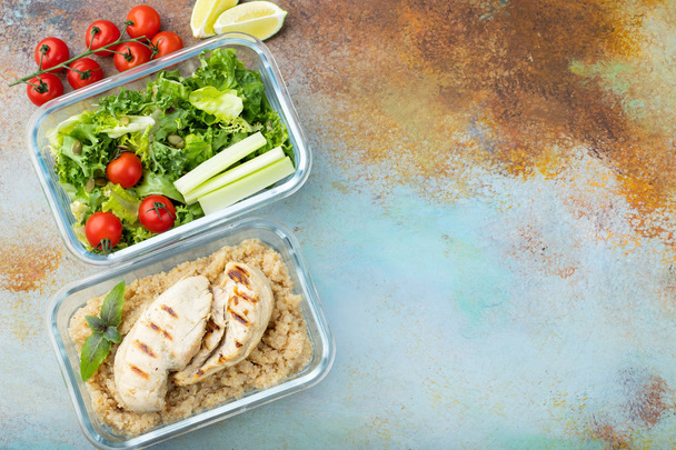 gesunde Mahlzeitenzubereitungsbehälter mit Quinoa, Hühnerbrust und grünem Salat über Kopf mit Kopierraum. Ansicht von oben. flache Lage. - Foto, Bild