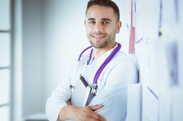 Young and confident male doctor portrait standing in medical office - Fotó, kép