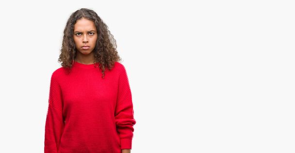 Mulher hispânica jovem vestindo camisola vermelha cético e nervoso, franzindo a testa chateado por causa do problema. Pessoa negativa
. - Foto, Imagem