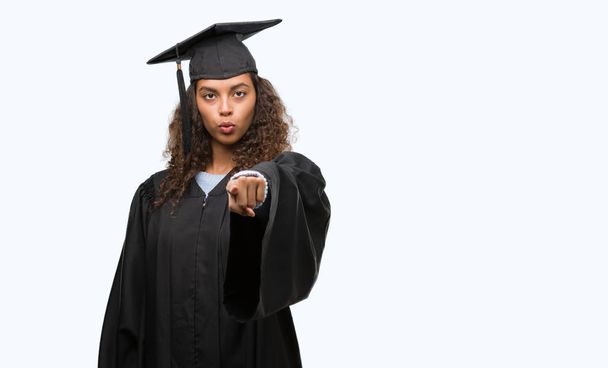 Young hispanic woman wearing graduation uniform pointing with finger to the camera and to you, hand sign, positive and confident gesture from the front - Фото, изображение