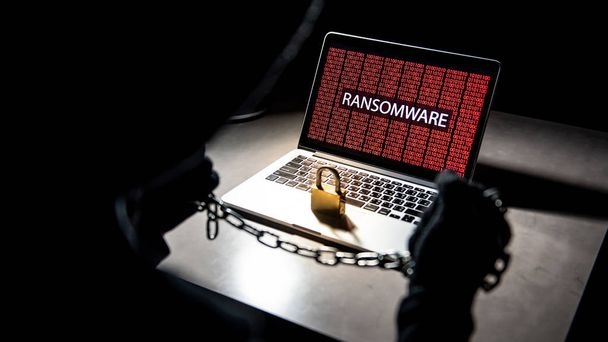 Mężczyzna anonimowe hacker blokowania komputera za pomocą łańcuch i kłódkę. Atak cybernetyczny i Internet koncepcja bezpieczeństwa danych - Zdjęcie, obraz