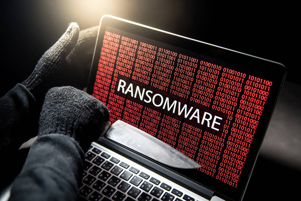 Αρσενικό χάκερ threading φορητό υπολογιστή με μαχαίρι που εμφανίζεται στην οθόνη με κόκκινα ψηφιακό δυαδικό ransomware προειδοποίηση. Cyber επίθεση και internet έννοια ασφάλειας δεδομένων - Φωτογραφία, εικόνα