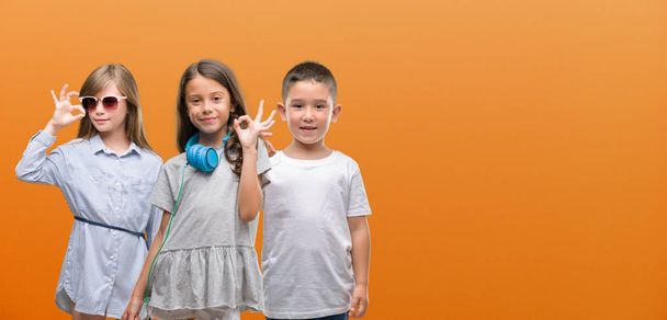 A fiú és a lányok gyerekek felső narancssárga háttérben ujjaival, kiváló szimbólum ok jele - Fotó, kép
