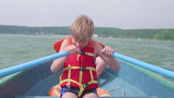 De man drijft op de boot. Tiener opereert zelfstandig een boot met de hulp van de roeiriemen. Extreme sporten - Video