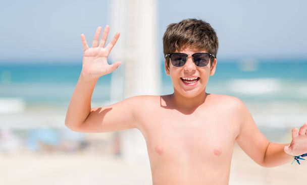 Bambino in vacanza sulla spiaggia molto felice ed eccitato, espressione vincente che celebra la vittoria urlando con grande sorriso e mani alzate
 - Foto, immagini