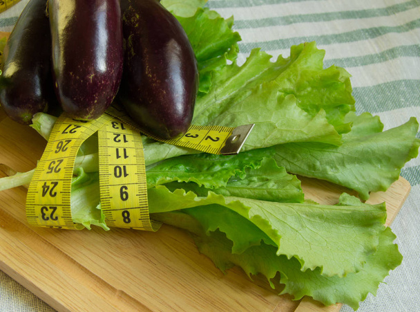 The concept of diet, healthy eating, lettuce, eggplant, measuring tape - Photo, Image