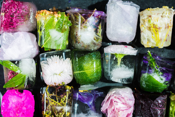 Jäädytetyt kevätkukat jääkuutioissa tummalla pohjalla
 - Valokuva, kuva
