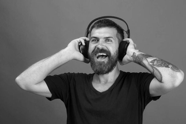 Dj with beard wears headphones. Relax and music concept. Singer with beard and smiling face - 写真・画像