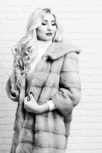 blonde hair in waist coat of grey fur and fashion makeup on brick wall studio background. fashionable sexy woman in fur - Фото, зображення