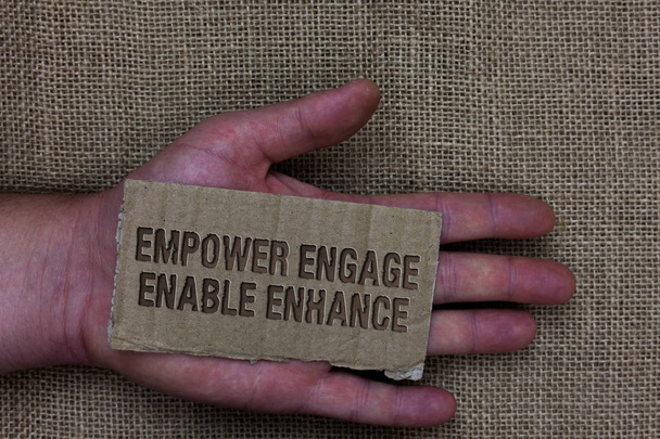 Conceptual hand writing showing Empower Engage Enable Enhance. Business photo text Empowerment Leadership Motivation Engagement Cardboard with marked some letters on human hand jute sack ground - Photo, Image