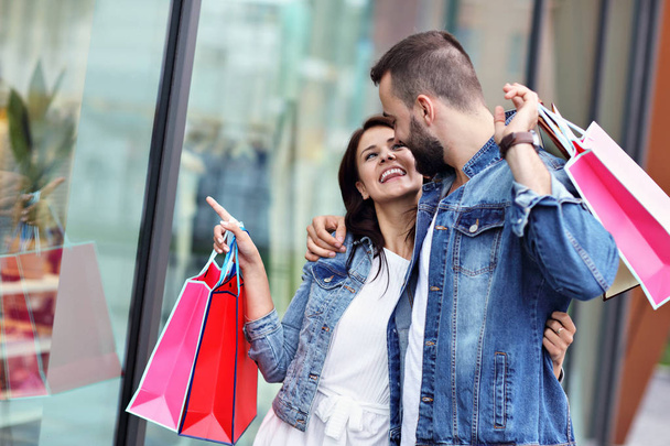 Πορτρέτο του ευτυχισμένου ζευγαριού με τσάντες ψώνια μετά τα ψώνια στην πόλη - Φωτογραφία, εικόνα