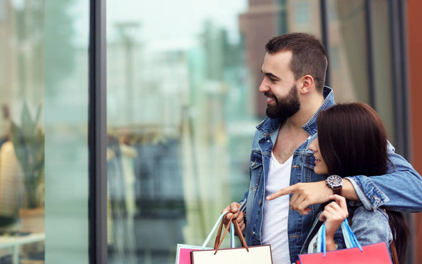 Portrait of happy couple with shopping bags after shopping in city - Фото, изображение