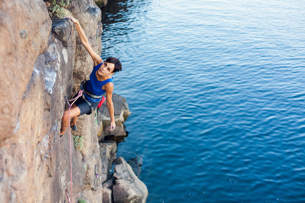 Horolezec holka šplhá skále nad vodou. Outdoorové aktivity. extrémní sport - Fotografie, Obrázek
