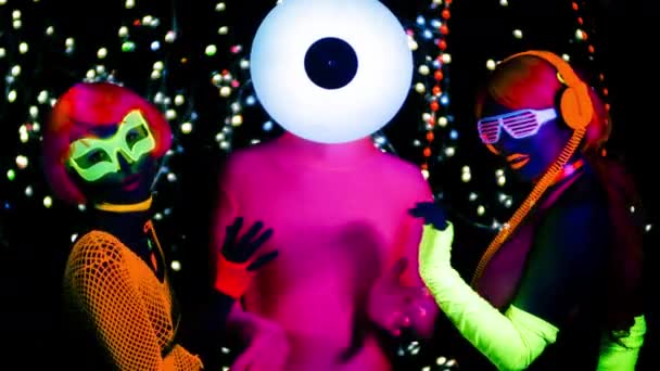 Сексуальные женщины и мужчина танцуют с виниловой головой в флуоресцентной одежде под ультрафиолетовым светом
. - Кадры, видео