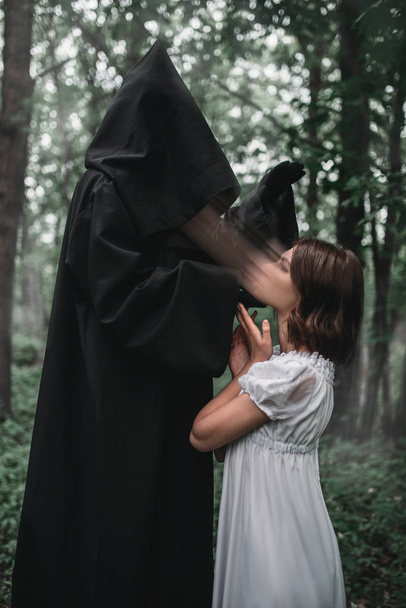 Ölümün içinde siyah kapüşonlu genç kadın kurban, arka plan üzerinde orman ruhu vardır. Korku tarzı, gizem ritüel fotoğraf - Fotoğraf, Görsel
