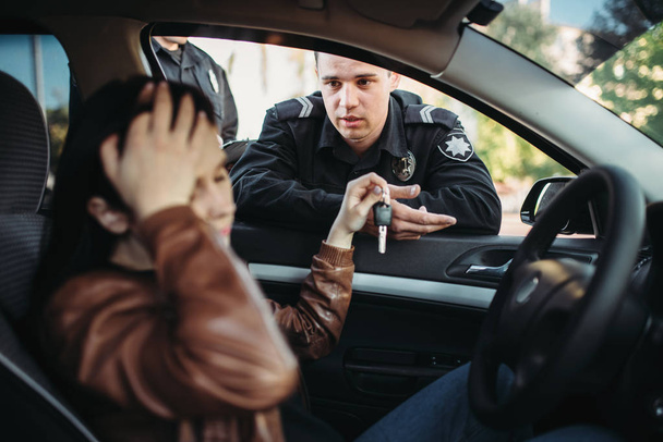 Férfi zsaru az egységes ellenőrzés női vezető úton. Jogi védelem, autó forgalom ellenőr, biztonsági ellenőrzési munka - Fotó, kép