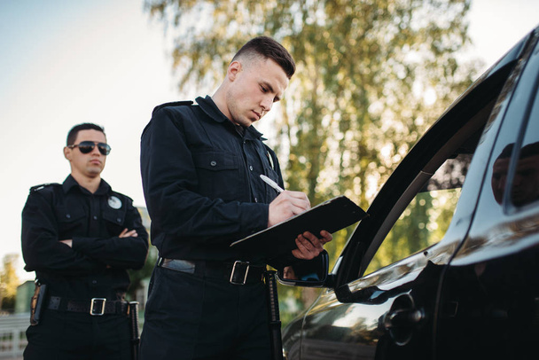 Policjantów mężczyzna w mundurze sprawdzanie pojazdu na drodze. Ochrony prawa, inspektor ruchu samochodu, zadanie kontroli bezpieczeństwa - Zdjęcie, obraz