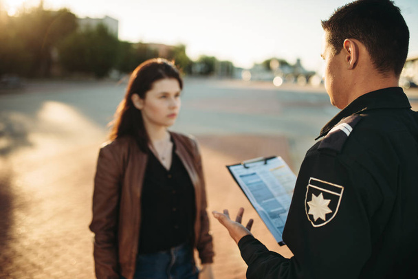 Politieagent in uniform leest wet aan vrouwelijke bestuurder. Wet bescherming, auto verkeer inspecteur, veiligheid controle baan - Foto, afbeelding