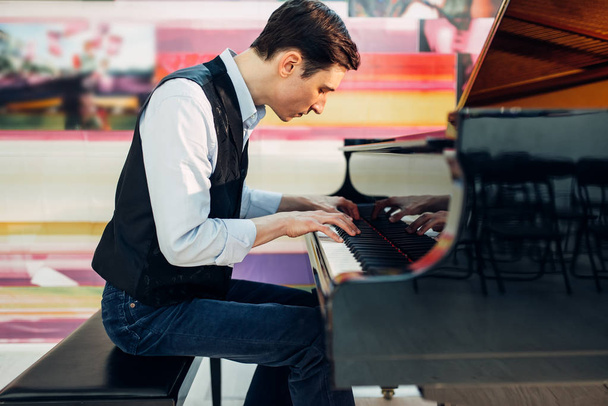 Male pianist practicing composition on grand piano. Musician plays melody at the royale, classical musical instrument - Photo, image