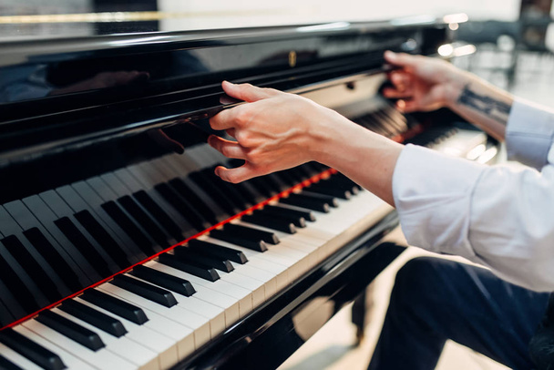 Αρσενικό πιανίστα ανοίγει το καπάκι του πληκτρολογίου από το μαύρο πιάνο. Μουσικός ετοιμάζεται να απόδοση για το royale, κλασικό μουσικό όργανο - Φωτογραφία, εικόνα
