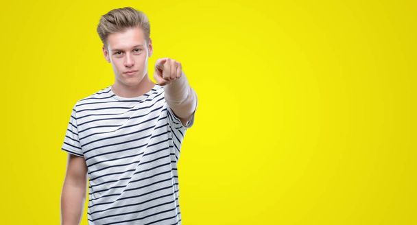 Mladý pohledný blond muž nošení pruhy námořník tričko ukazující prstem na kameru a vám, ručně podepsat, pozitivní a sebevědomý gesto zepředu - Fotografie, Obrázek