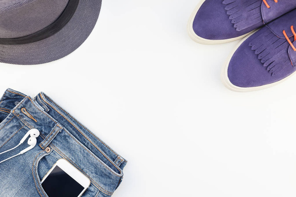 Flache Wildlederschuhe, blaue Jeans, grauer Hut, Kaktus und Smartphone mit Kopfhörer auf weißem Hintergrund mit Kopierraum. Overhead-Ansicht der Frau Casual Outfit. trendiger Hipster-Look von oben - Foto, Bild