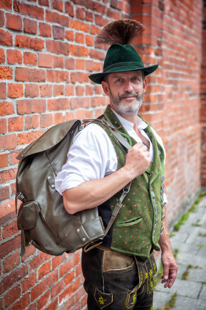 portrait of handsome bavarian man standing outside with backpack - Zdjęcie, obraz