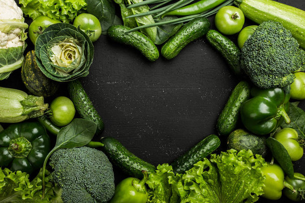 Valikoima tuoreita vihreitä vihanneksia sydämen kunnossa tummalla taustalla, ylhäältä
 - Valokuva, kuva