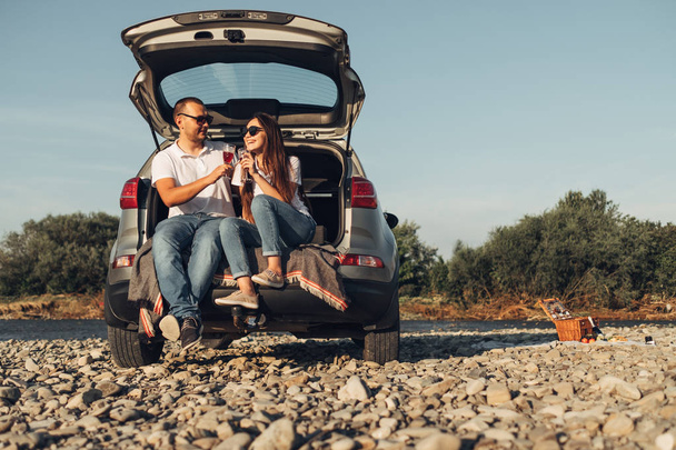 Couple voyageur heureux sur pique-nique dans le coucher du soleil avec voiture SUV
 - Photo, image