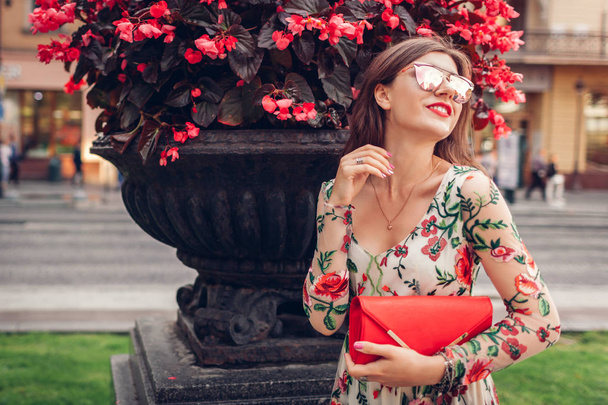 Young woman wearing classic dress with accessories outdoors. Stylish outfit. Fashionable look. Lady posing on city street - 写真・画像