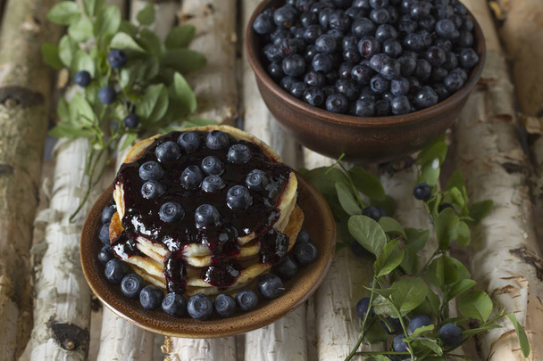 Pancakes with blueberry jam and blueberries on a wooden birch background. - Foto, afbeelding