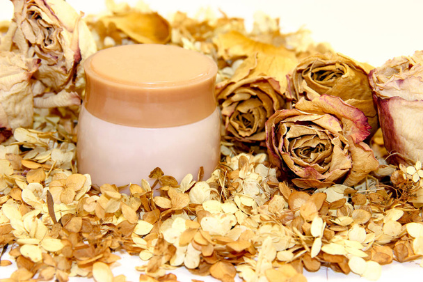 un vaso di crema tra petali sparsi di ortensia e fondo di fiori di rosa
 - Foto, immagini