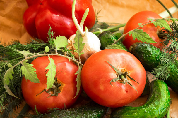 Организация на оберточной бумаге ассортимента свежих овощей, красный перец, чеснок, зеленый лук, помидоры, огурцы
 - Фото, изображение