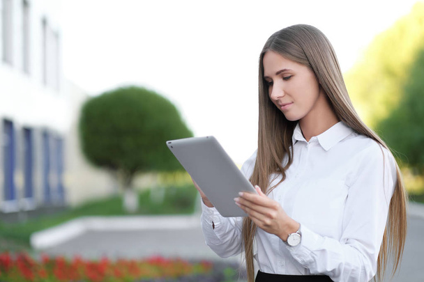 Young beautiful businesswoman student businesswoman uses tablet outdoor - 写真・画像