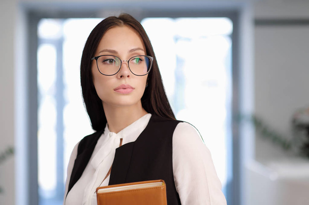 Lány tanuló vagy tanár az irodában. Szemüveg- és jelmeztervező, a kezében egy notebook. - Fotó, kép