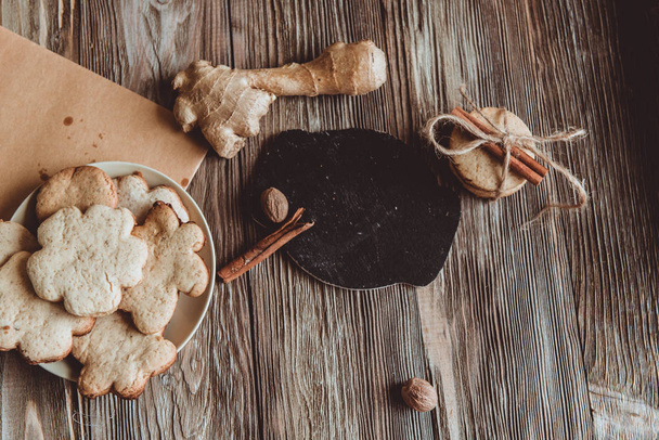 Primo piano di biscotti allo zenzero fatti in casa, cannella, zenzero su un tavolo di legno. Ricevuto. Vintage immagine tonica, posa piatta
 - Foto, immagini