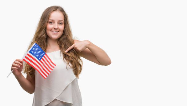 ABD bayrağı sürpriz yüz işaret parmağı kendisine tutan genç sarışın kadın - Fotoğraf, Görsel
