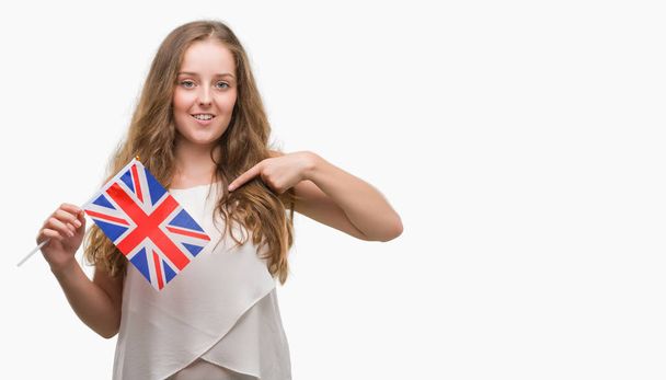 Молодая блондинка с флагом Великобритании с неожиданным лицом, указывающим пальцем на себя
 - Фото, изображение